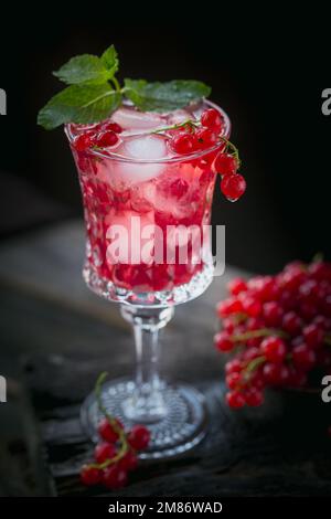 Boisson d'été avec vin blanc mousseux. Cocktail de fruits frais ou punch fait maison avec champagne, cassis, glaçons et feuilles de menthe Banque D'Images