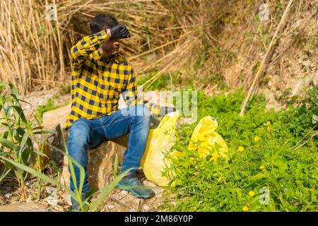 Une personne portant des gants et collectant des plastiques dans une forêt, concept d'écologie Banque D'Images
