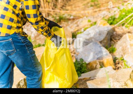 Une personne portant des gants et collectant des plastiques dans une forêt, concept d'écologie Banque D'Images