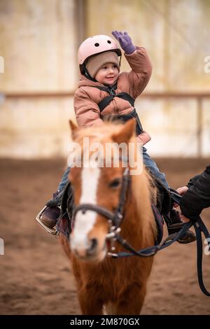 Leçon de équitation pour les petits enfants. Une jeune fille de trois ans fait du poney et fait des exercices Banque D'Images