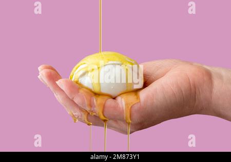 La femme tient une boule de mozzarella dans sa main et verse de l'huile d'olive. Apéritif italien, mozzarella et huile d'olive. Banque D'Images