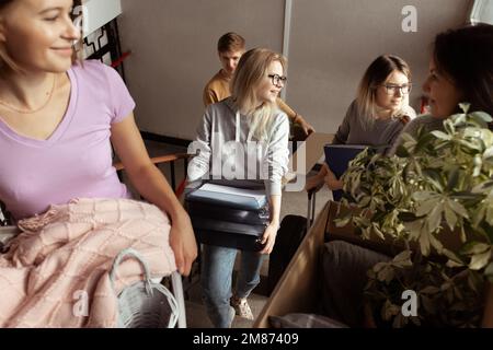 Souriant, anticipant les étudiants portent leurs bagages et tout ce qui se trouve dans les escaliers, parlez. Nouveau quartier de campus, colocation en vacances Banque D'Images