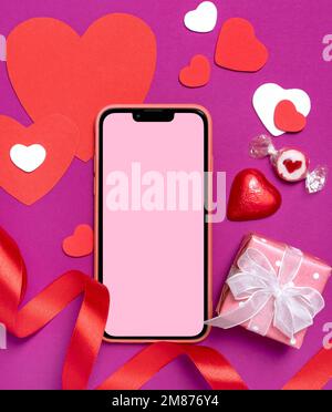 Arrière-plan des fêtes avec smartphone sur fond rose. Contexte de la Saint-Valentin Banque D'Images