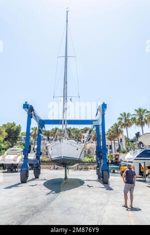 Dans le chantier naval de Porto Cristo, Majorque, une grue lève ce voilier à terre pour inspection. Banque D'Images