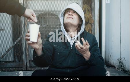 L'homme sans domicile s'assoit sur les marches et demande de l'aide et de l'argent. Banque D'Images