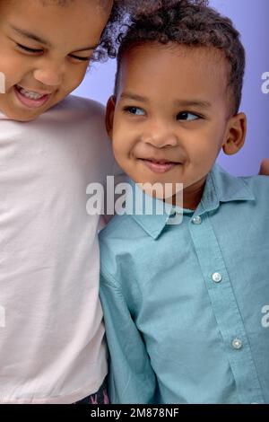 Portrait de deux petits amis noir gai beau frère et soeur ayant l'amusement isolé sur fond violet studio, adorables enfants avec curl Banque D'Images