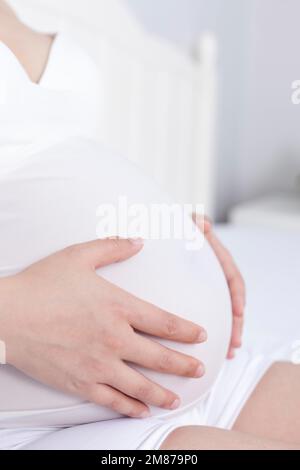 Les femmes enceintes se sont assises sur le lit pour se reposer Banque D'Images