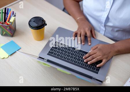 vue de dessus sur les mains noires de femmes dactylographiant sur le clavier d'ordinateur portable, travaillant en ligne sur le bureau. copier l'espace. courte femme méconnue en chemise blanche. les gens, busi Banque D'Images