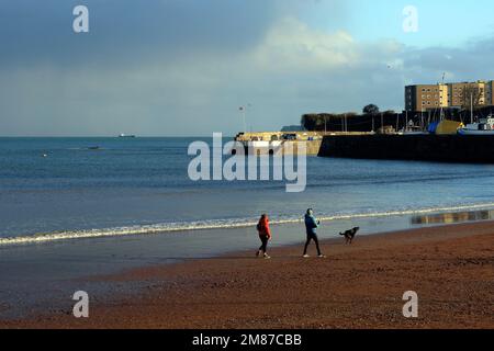 Plage de Paignton, vue vers l'entrée du port avec des randonneurs qui profitent du soleil d'hiver. Paignton, pris en janvier 2023. Hiver Banque D'Images