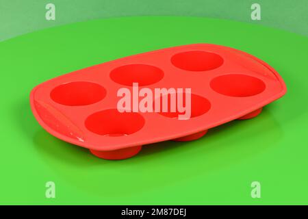 Forme en silicone rouge pour cuire le muffin et le cupcake sur fond vert. Vue latérale. Photo haute résolution. Profondeur de champ complète. Banque D'Images