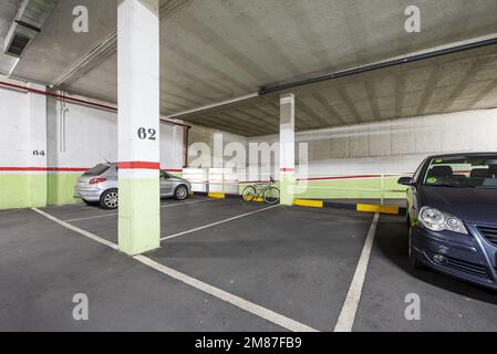 Garage récemment construit avec de grands espaces et des voies avec des planchers en béton, des lignes blanches peintes sur le plancher et des véhicules garés Banque D'Images