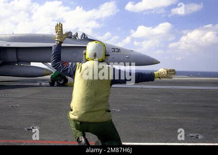 Un membre de l'équipage du pont de vol signale au pilote un F/A-18 Hornet qui a été préparé pour le lancement à bord du porte-avions à propulsion nucléaire USS THEODORE ROOSEVELT (CVN-71). Pays : inconnu Banque D'Images