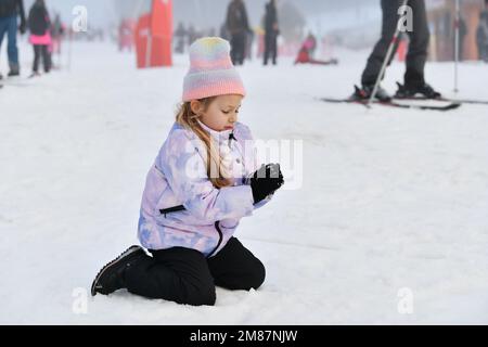 Une petite fille qui fait des boules de neige à l'extérieur le jour d'hiver Banque D'Images