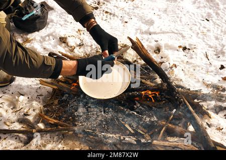 homme de tourisme cultivé faisant un repas sur feu de camp dans la forêt, en forêt d'hiver, nature. un homme méconnu qui voyage, un concept de brousse. vie active et saine Banque D'Images