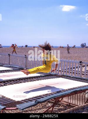 Adolescente sautant sur trampoline, Plage de l'Écluse, Dinard, Ille-et-Vilaine, Bretagne, France Banque D'Images