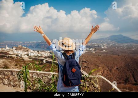 Hôtels Santorin avec sac à dos, bras levés se sentir heureux à à Akrotiri, paysage montagneux sur l'île. Tourisme Banque D'Images