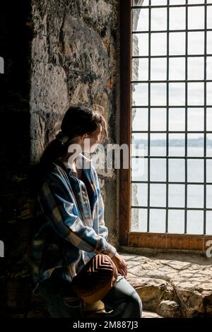 Adolescente regardant une fenêtre dans l'abbaye d'Inchcolm sur l'île dans le Forth de Firth Banque D'Images