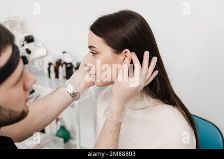 L'otoplastie est un remodelage chirurgical de la pinna ou de l'oreille externe pour corriger une irrégularité et améliorer l'apparence. Le médecin chirurgien examine l'oreille de fille b Banque D'Images