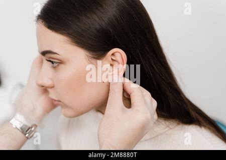 L'otoplastie est un remodelage chirurgical de la pinna ou de l'oreille externe pour corriger une irrégularité et améliorer l'apparence. Le médecin chirurgien examine l'oreille de fille b Banque D'Images