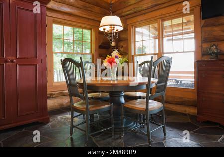 Table à manger antique en bois rond avec chaises à dossier haut dans la salle à manger à l'intérieur de la maison en rondins d'épicéa scandinave artisanale. Banque D'Images