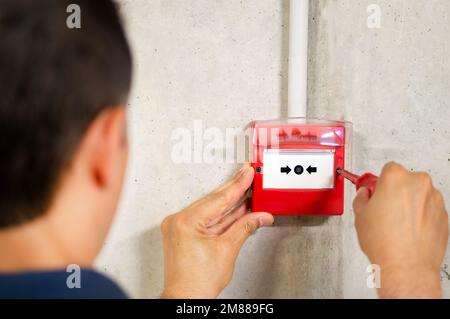 Vue arrière de l'installation d'un système d'alarme incendie par un électricien Banque D'Images