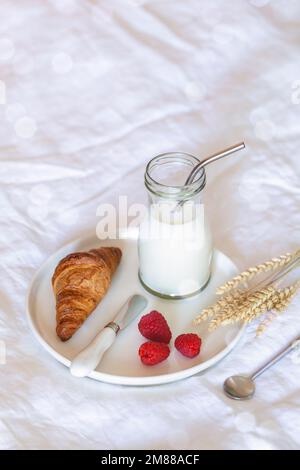 petit déjeuner français sur un lit, croissant, lait et baies fraîches, espace de photocopie Banque D'Images