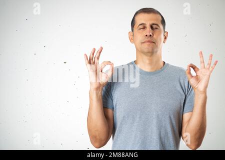 Jeune homme caucasien sur le mur isolé arrière-plan se détendre et sourire avec les yeux fermés faisant un geste de méditation avec les doigts et l'espace de copie. Yoga concep Banque D'Images