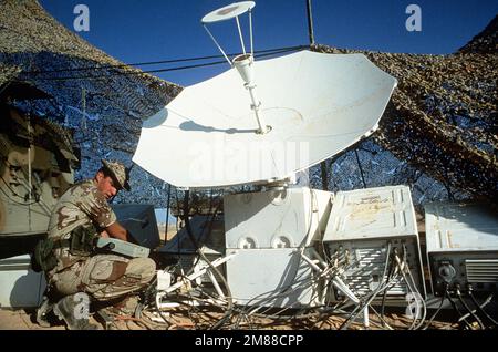 Le PETIT officier de la Marine 2nd classe John R. Horton, membre de l'élément de soutien des communications conjointes, travaille sur une parabole satellite à haute fréquence pendant l'exercice Shadow Hawk, une phase de Bright Star '87. États-Unis Exercice du commandement central/chefs d'ÉTAT-MAJOR interarmées pr. Objet opération/série: SHADOW HAWKBRIGHT STAR '87 base: Base aérienne de King Faisal État: Al Jafr pays: Jordanie (JOR) Banque D'Images