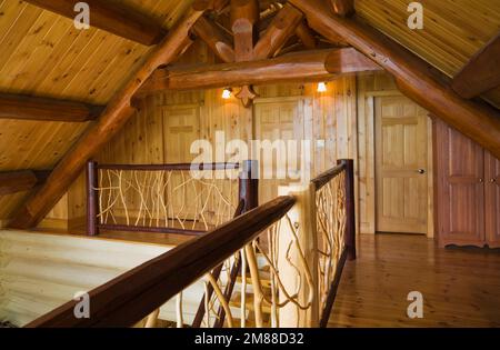 Balustrades en branches de cèdre et planchers en bois de pin rouge à l'étage à l'intérieur de la maison en rondins de style scandinave. Banque D'Images