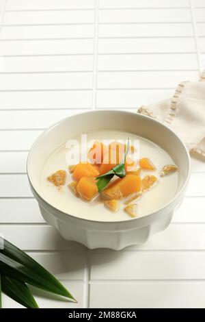 Lait de noix de coco cuit Pumpkin ou Kolak Labu, indonésien et thaï Sweet Dessert. Citrouille en tranches bouillie dans du lait de coco et du sucre de palme dans un bol blanc Banque D'Images