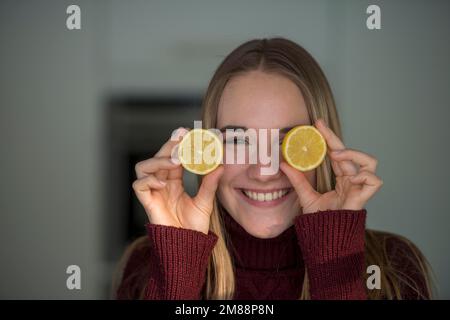 Jeune femme, couper des fruits, se moquer dans la cuisine, s'amuser avec les citrons, haute-Bavière, Bavière, Allemagne, Europe Banque D'Images