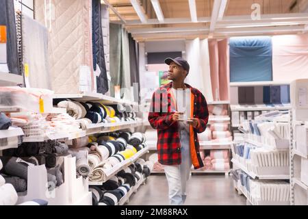 Homme ethnique noir qui fait du shopping dans un supermarché pour les tapis de bain et les serviettes Banque D'Images