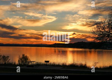 Coucher de soleil au parc national d'Inks Lake Burnet Texas USA. Une table de pique-nique et un barbecue donnent sur le magnifique lac doré de couleur coucher de soleil. Banque D'Images