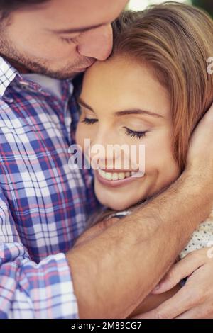 Shes totalement dévoué à lui. Gros plan d'un jeune couple souriant qui s'embrasse les uns les autres dans le parc. Banque D'Images