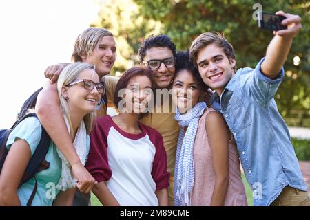 Prendre des photos de merveilleux souvenirs. Un groupe heureux d'étudiants d'université souriant pour une photo sur le point d'être prise. Banque D'Images