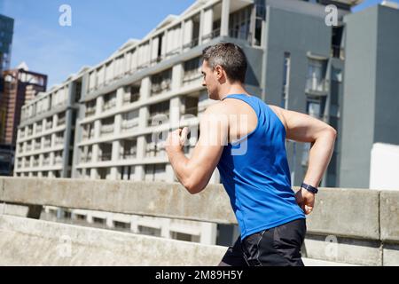 Le moyen le plus rapide de s'établir à la fois fort, rapide et pauvre : les sprints en pente. Jeune homme effectuant des sprints de colline sur les routes de la ville. Banque D'Images