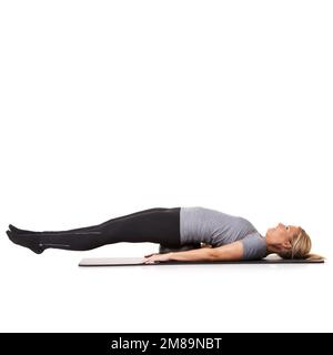 Sentir ses muscles tirer. Une jeune femme allongé sur une balle d'exercice et étendant ses jambes. Banque D'Images
