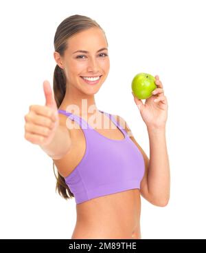 Pomme, pouces et fitness de la femme en studio isolé sur fond blanc. Visage, portrait et modèle féminin avec geste de main et fruit pour la santé Banque D'Images