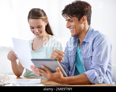 L'équipe pour faire le travail. Deux jeunes entrepreneurs travaillant ensemble sur une tablette numérique. Banque D'Images