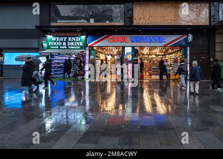 Cool Britannia boutique de souvenirs, Leicester Square, Londres, Royaume-Uni. Le tourisme britannique. Avant du magasin. Avant du magasin. Les gens passent la soirée d'hiver humide et pluvieux Banque D'Images