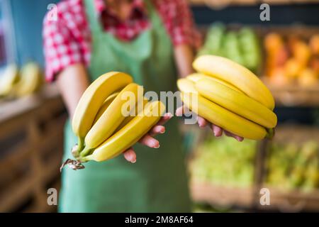 Le travailleur de la boutique de fruits et légumes tient des bananes. Gros plan sur les bananes. Banque D'Images