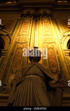 La belle lumière dorée, éthériale et sainte traverse des fenêtres et s'élève sur un mur derrière une sculpture emblématique de l'église catholique baroque, Basilica o Banque D'Images