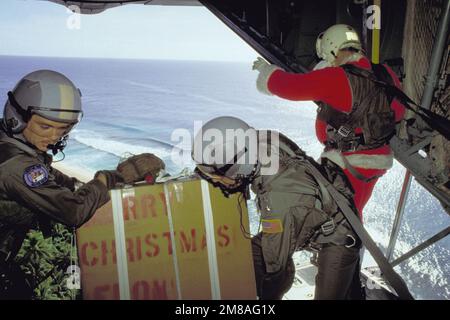 Les membres du personnel des escadrons de transport aérien tactique de 345th et 21st se préparent à libérer un colis de la baie de chargement de leur avion Hercules C-130, alors que le Père Noël (MGÉN Alexander K. Davidson, commandant de la Force aérienne de 22nd) se tient à côté. Les dons de Noël sont parachutés sur les îles locales. État : FS Micronésie (FM) pays : États-Unis d'Amérique (USA) Banque D'Images