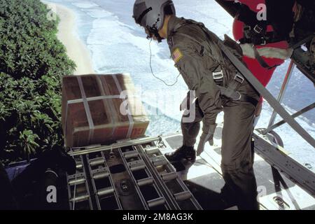 Le personnel des escadrons de transport aérien tactique de 345th et 21st libère un colis de la baie de chargement d'un avion C-130 Hercules. Les dons de Noël sont parachutés sur les îles locales. État : FS Micronésie (FM) pays : États-Unis d'Amérique (USA) Banque D'Images