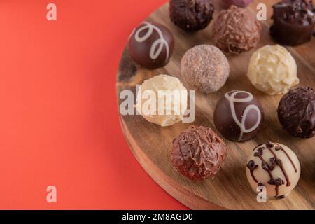 photo de chocolats ronds sur une planche en bois gros plan sur un fond rouge Banque D'Images