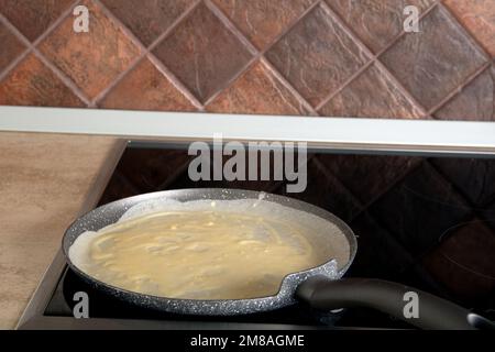 photo de la pâte à frire sur une poêle pour des crêpes sur la cuisinière dans la cuisine Banque D'Images