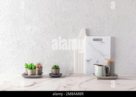 partie de l'intérieur d'un comptoir de cuisine moderne avec planches à découper en marbre blanc et succulents dans des pots de fleurs. minimalisme Banque D'Images