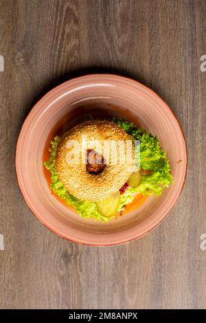 Vue de dessus de l'assiette avec hamburger appétissant avec trou dans le pain, laitue, poulet frit, concombres marinés sur une table en bois. Banque D'Images