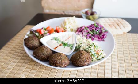 Plat combiné de falafel avec légumes. Faláfel ou falafel​ est une croquette de pois chiches ou de fèves. Il est généralement consommé au Moyen-Orient. Banque D'Images