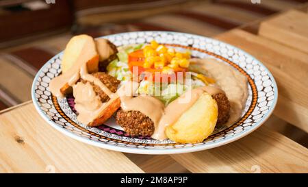 Plat combiné de falafel avec légumes. Faláfel ou falafel​ est une croquette de pois chiches ou de fèves. Il est généralement consommé au Moyen-Orient. Banque D'Images